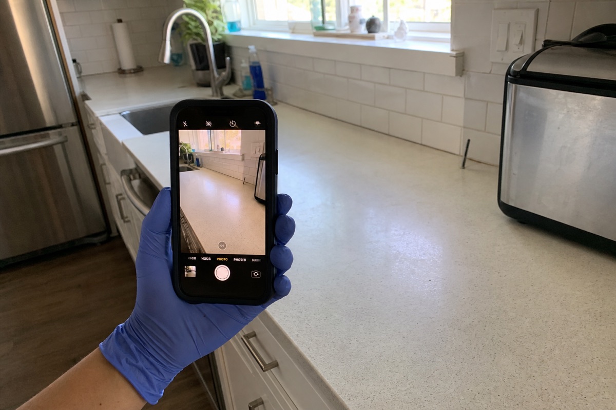 A cleaner photographing a finished kitchen as proof of work