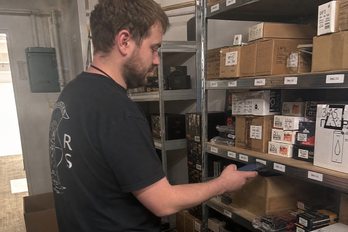 A worker doing a stock count with a phone in a stockroom